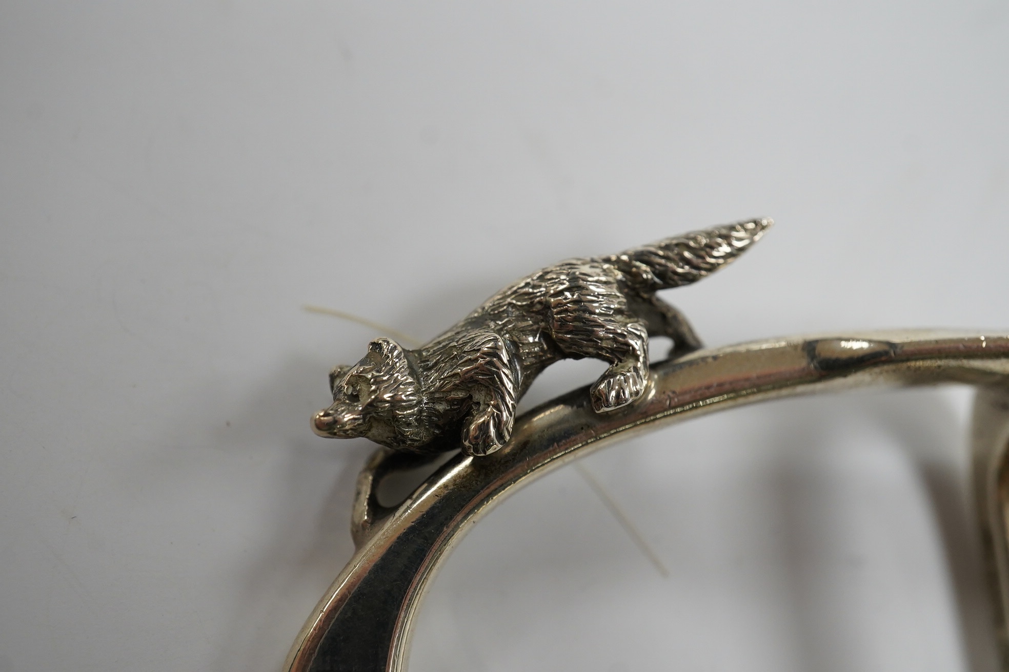 A George VI silver napkin ring modelled as a stirrup, surmounted with a fox, Birmingham, 1937, 46mm, together with a later silver horses head snuff box and a silver pill box with fox surmount. Condition - fair to good